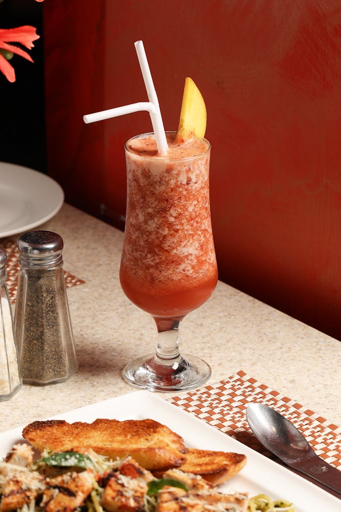 Vibrant fruit smoothie served alongside grilled chicken with toast, capturing a healthy meal setup.